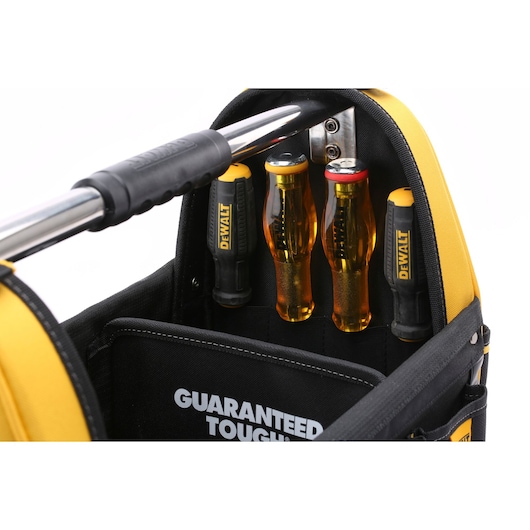 Close-up of a DEWALT tool bag with a metal handle and several DEWALT branded screwdrivers stored upright in inside pockets. The words 'GUARANTEED TOUGH' are visible on a black inner panel.