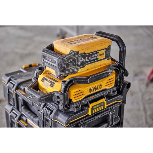Close-up of a DEWALT Power Shift battery and charging module stacked on ToughSystem tool storage boxes, designed for construction and job site use.