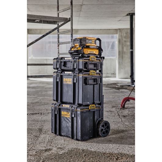 Stacked DEWALT ToughSystem toolboxes and organizers with wheels, shown in a construction site setting.