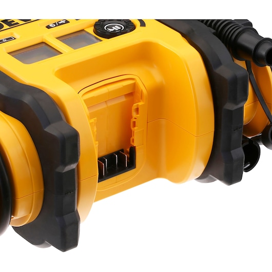 Close-up view of a yellow DEWALT device showing a battery slot and part of the control panel, with rugged black accents.