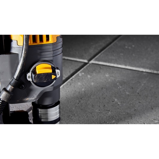 Close-up of a DEWALT power tool with a yellow and black switch, positioned on a tiled concrete floor.