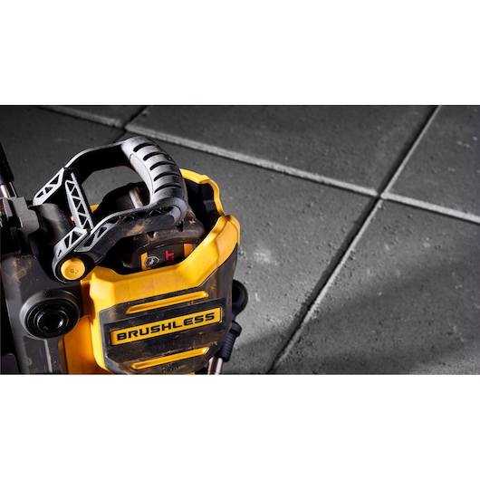 Close-up of a DEWALT brushless power tool with a robust black and yellow handle, positioned on a grey tiled surface.