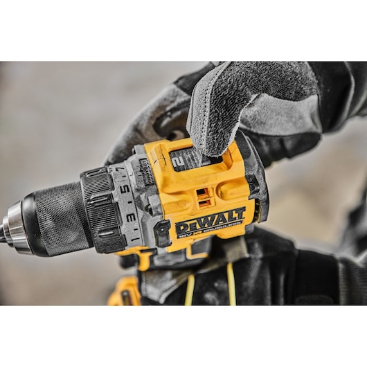 Close-up of a DEWALT DCD800H2T cordless drill being adjusted by a gloved hand.