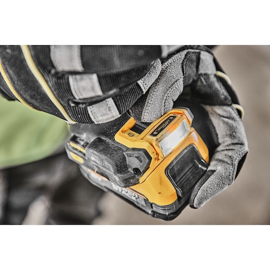 Close-up of a gloved hand holding a DEWALT power tool, specifically focusing on the handle and LED light.