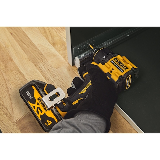 A DEWALT DCD803 cordless drill being used to install screws in a metal rail on a wooden surface.