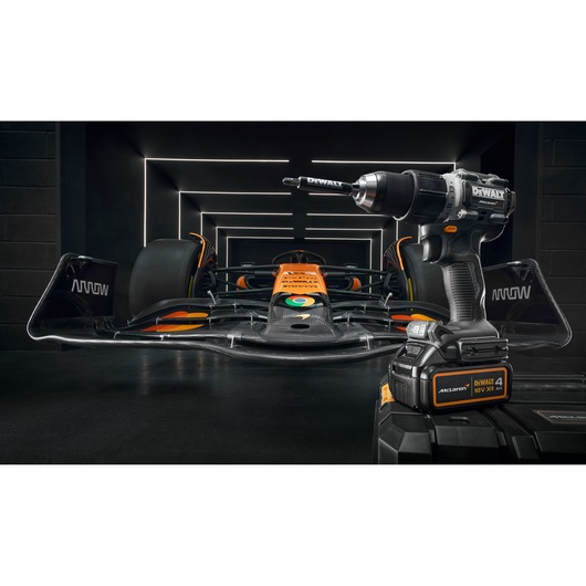 A DEWALT cordless drill is displayed in the foreground, with a black and orange Formula 1 race car parked inside a tunnel with illuminated geometric lines in the background.