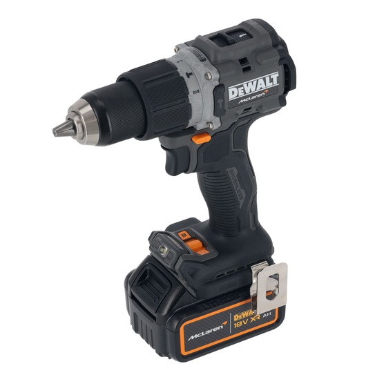 A DEWALT McLaren cordless power drill with an 18V XR battery. The drill is black and grey with orange accents and has a metal belt clip attached to the base.