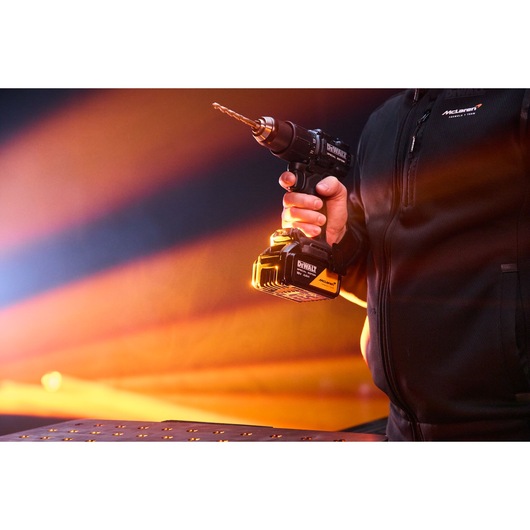 A hand holds the DEWALT x McLaren F1 Team 18V XR Special Edition Hammer Drill Driver with 4Ah battery