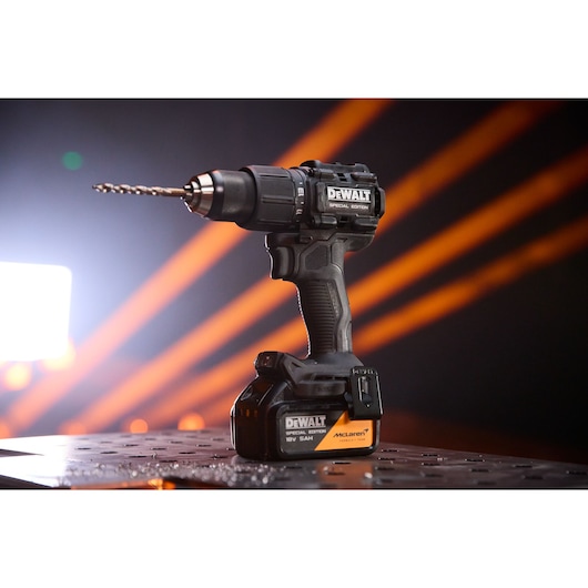 DEWALT x McLaren F1 Team 18V XR Special Edition Hammer Drill Driver with 5Ah battery standing on a metal sheet