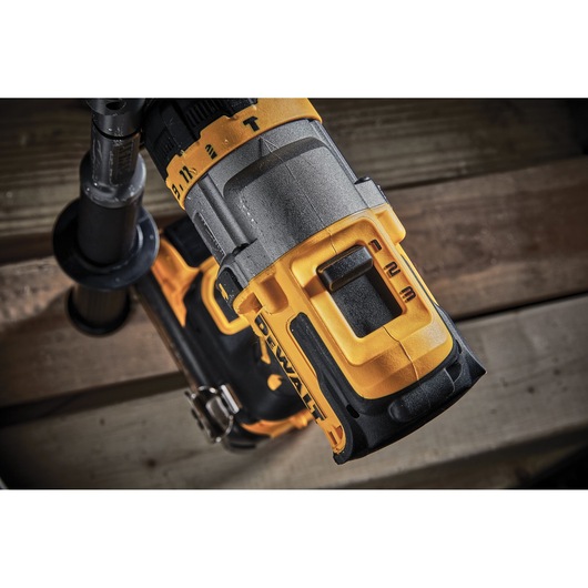 Close-up view of a DEWALT cordless drill, showing the yellow and black body, focusing on the gearbox and speed selector switch.