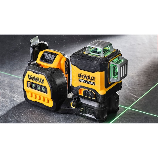 DEWALT 12V/18V green line laser level device set shown on a surface, emitting bright green laser lines for precise alignment.