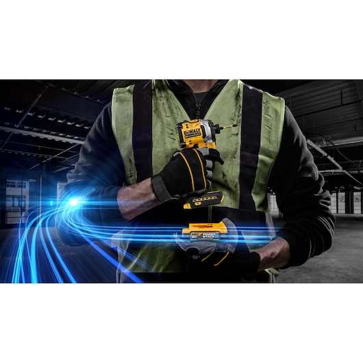 A person wearing a green safety vest and black gloves is holding a yellow DEWALT cordless impact driver with a battery pack. Blue light trails are illustrated across the image, emphasizing power and technology.