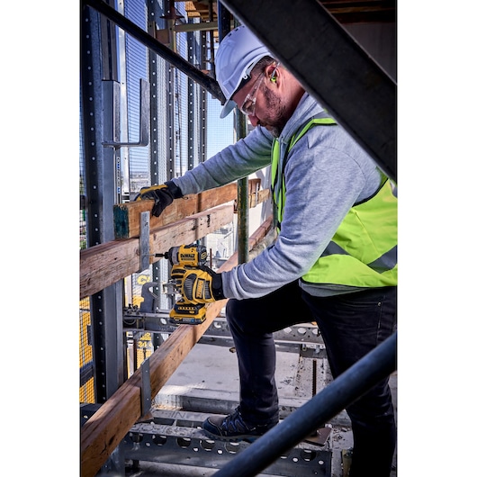 Worker uses DEWALT DCF860N-XJ, DCF860N on site, wearing safety gear. Photography product category.