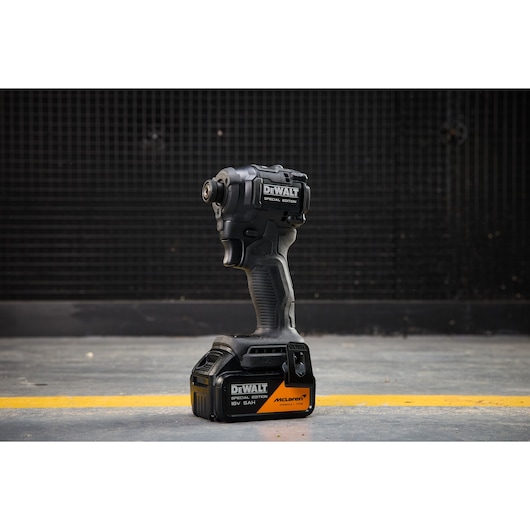 DEWALT x McLaren F1 Team 18V XR Special Edition Impact Driver with 5Ah battery standing on a concrete floor