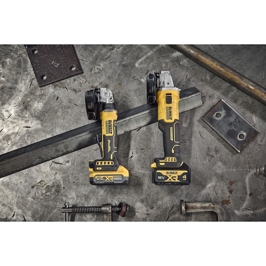 DEWALT DCG404NT and DCG404S2T-QW grinders on a metal workbench with tools. Photography product category.