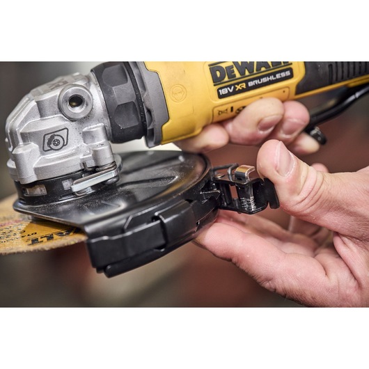 Close-up of hands adjusting the guard on a DEWALT 18V XR brushless angle grinder.