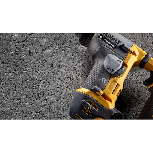 Close-up view of a DEWALT 18V XR brushless power tool with a yellow and black handle, placed on a rough concrete surface.