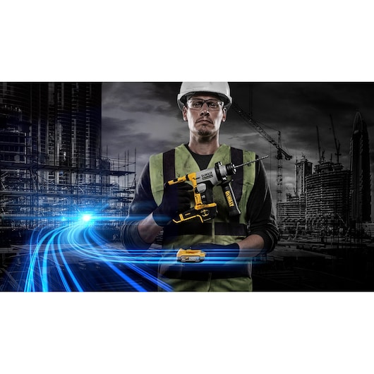 A construction worker wearing a safety helmet and high-visibility vest is holding a DEWALT cordless rotary hammer drill. The background features a modern construction site with cranes and buildings, and dynamic blue light trails in the foreground. The worker’s face is blurred.