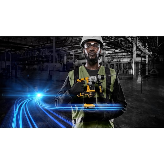 A person wearing a hard hat and safety vest holds a DEWALT cordless rotary hammer drill (SKU: DCH172E2T) in an industrial environment, with blue light streaks in the foreground and factory machinery in the background. The person's face is blurred for privacy.
