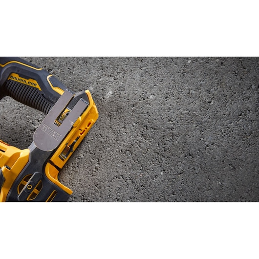 Close-up of a yellow and black DeWalt brushless power tool, partially visible, placed on a rough concrete surface.