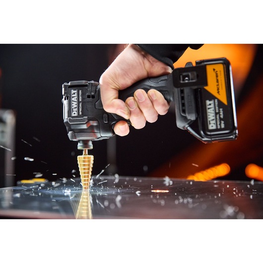 DEWALT x McLaren F1 Team 18V XR Special Edition Compact Impact Driver with 4Ah battery drilling a metal sheet with a step drill bit