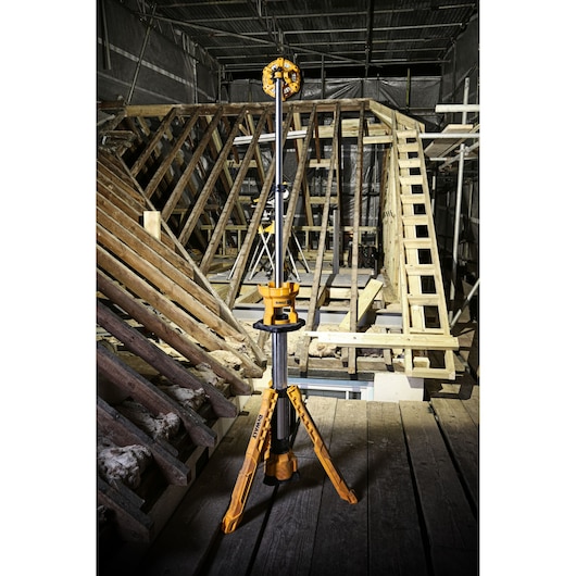 DEWALT DCL079 tripod work light positioned on a construction site with wooden beams and scaffolding.