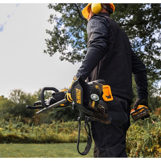 DEWALT DCMASED57X1, DCMASED9N brush cutter held outdoors by person wearing safety gear, photography category.