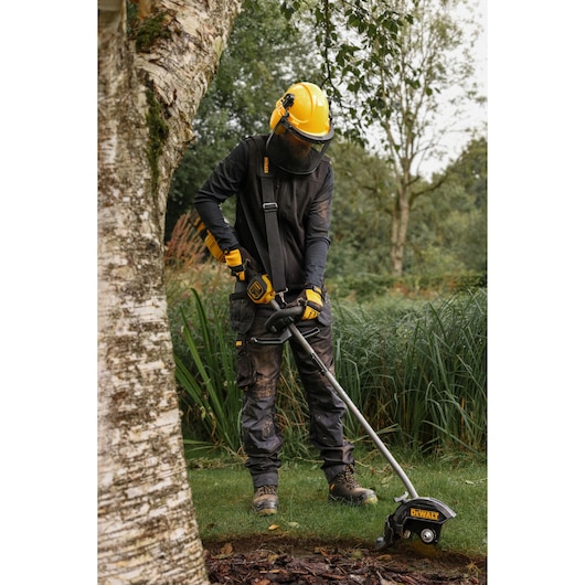 DEWALT DCMASED9N, DCMASED9N-XE edger used outdoors by person in protective gear; product for Photography category.