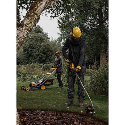DEWALT DCMASED9N, DCMASED9N-XE photography: two people using lawn tools outdoors. Product category: Photography.