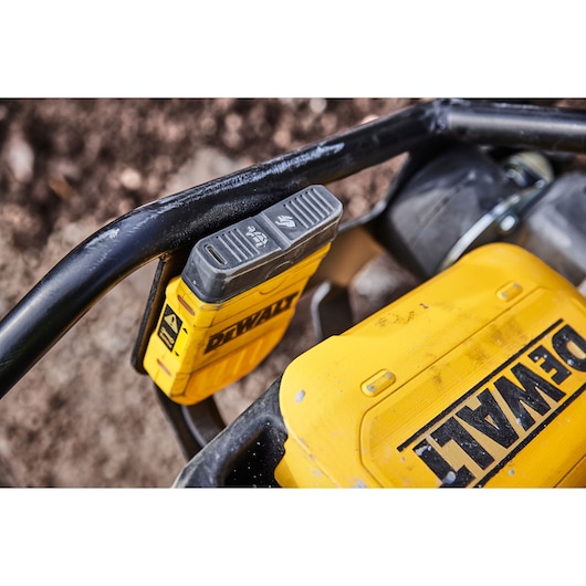 Close-up view of a DEWALT branded yellow power tool featuring a battery pack attached, with part of the tool frame visible.