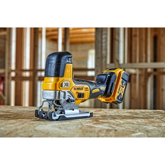 DEWALT cordless jigsaw, model DCS335P2, placed on a wooden surface at a construction site.