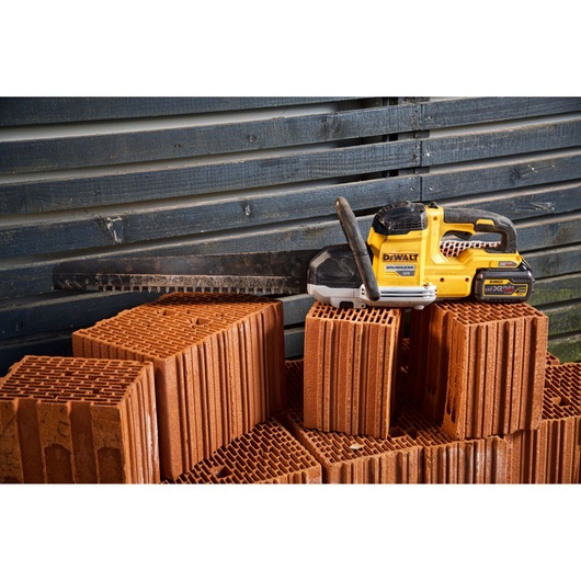 DEWALT masonry saw placed on stacked hollow bricks, with a dark wood wall in the background.