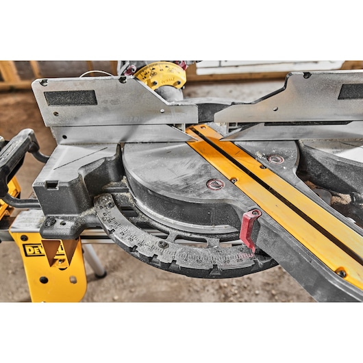 Close-up of a DEWALT miter saw with a yellow guide rail and angle adjustment used for precise cutting.