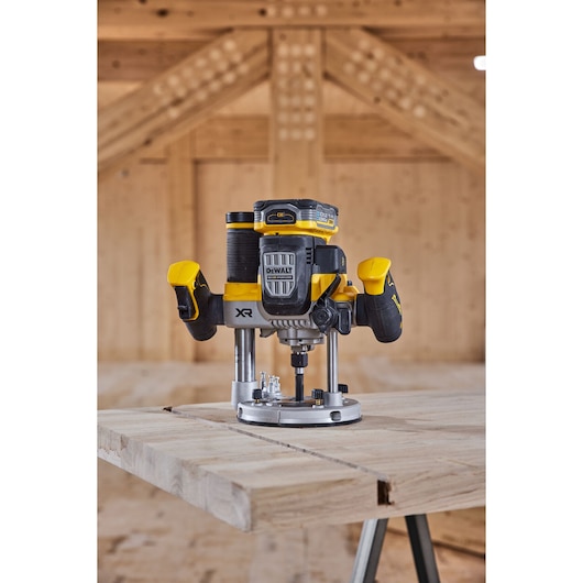 A DEWALT cordless router tool is placed on a wooden workbench, positioned inside a timber structure, ready for woodworking tasks.