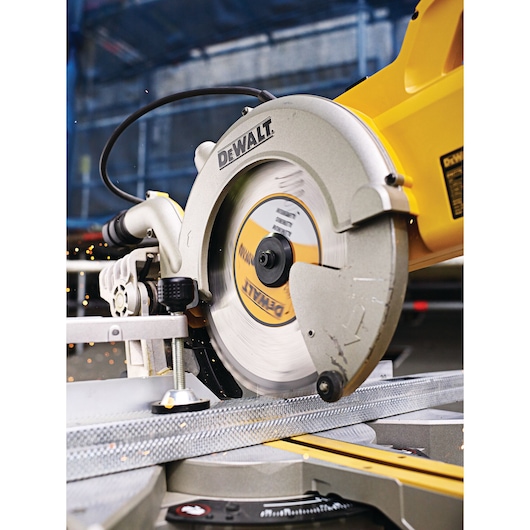 Close-up of a DEWALT circular saw cutting through a piece of metal, with sparks visible during operation.
