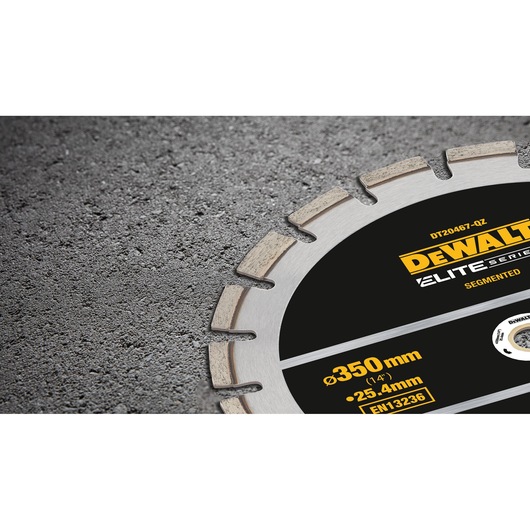 Close-up of a DEWALT segmented circular saw blade from the Elite Series, partially embedded in a rough concrete surface. The blade is labeled DT20467-QZ and indicates specifications of 350mm diameter and 25.4mm arbor size.