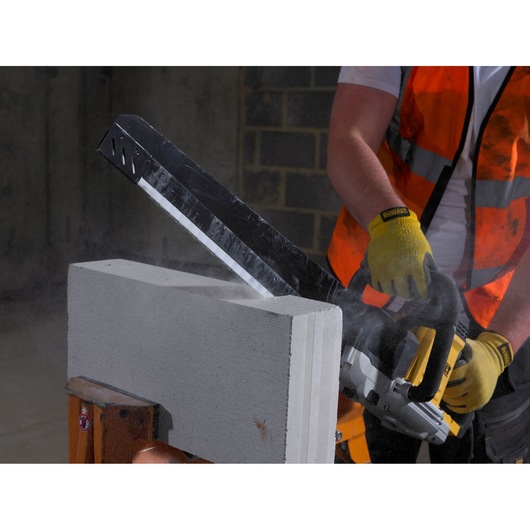 Worker uses DEWALT saw to cut concrete block, wearing gloves and safety vest.