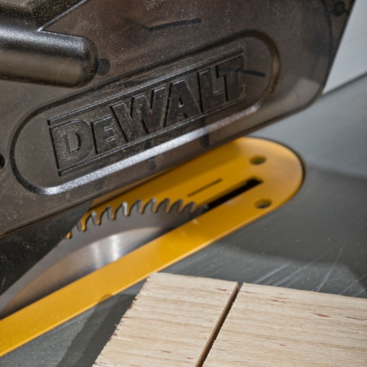 Close-up of DEWALT circular saw cutting wood, blade partially visible under the protective guard.