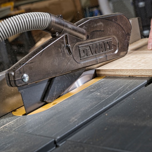 DEWALT saw blade cutting wood with dust extraction guard in workshop.