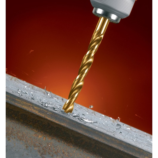 A close-up image of a gold-colored DEWALT drill bit drilling into a metal surface, with metal shavings scattered around the hole.