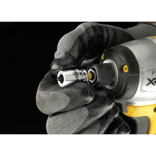 A close-up image showing a gloved hand inserting a DEWALT socket accessory into the chuck of a power tool, with the tool featuring a yellow and black design.