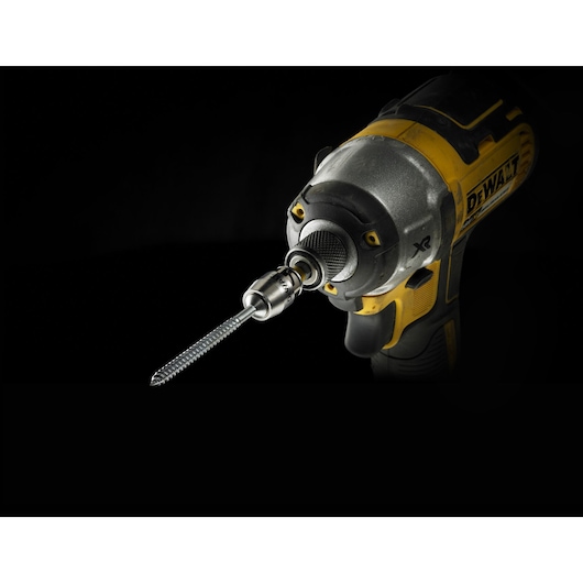 Close-up of a DEWALT power drill with a drill bit attached, set against a black background.