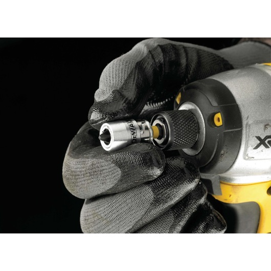 A gloved hand attaches a DEWALT socket adapter to a power tool with a black and yellow grip.