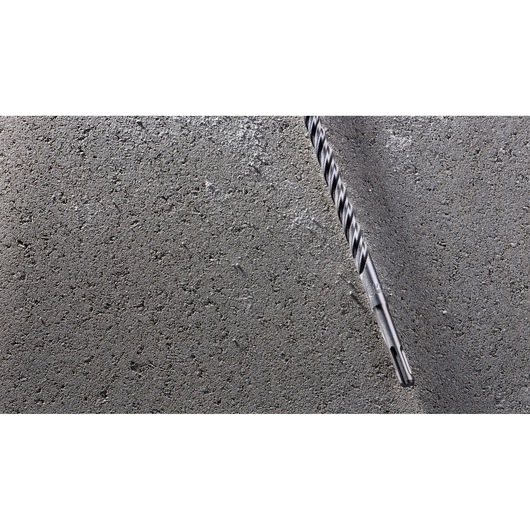 A DEWALT masonry drill bit embedded in a rough concrete surface.