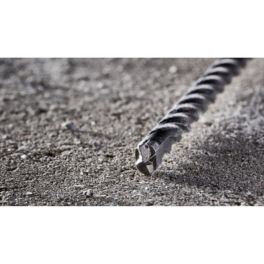 Close-up of a DEWALT DT8936 masonry drill bit lying on rough concrete surface.