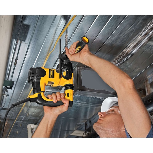 Person drills into metal ceiling using a yellow and black DEWALT power tool with a side handle.