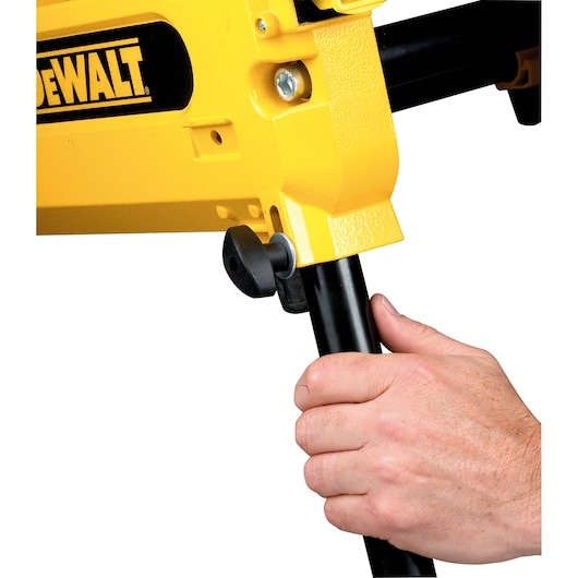 Close-up of a hand adjusting the leg of a yellow DEWALT power tool using a black knob.