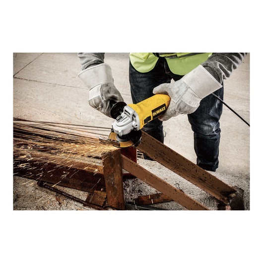 A person wearing safety gloves and a vest is using a yellow DEWALT angle grinder (model DWE4117) to cut through a metal beam, creating sparks.