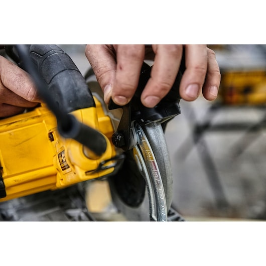 Close-up of a person adjusting the depth setting on a yellow DEWALT circular saw.
