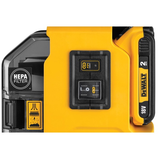 Close-up of a DEWALT device showing a HEPA filter compartment, control buttons, and an 18V 2Ah battery indicator. The device has a yellow and black design with clear labeling for filter and operation modes.